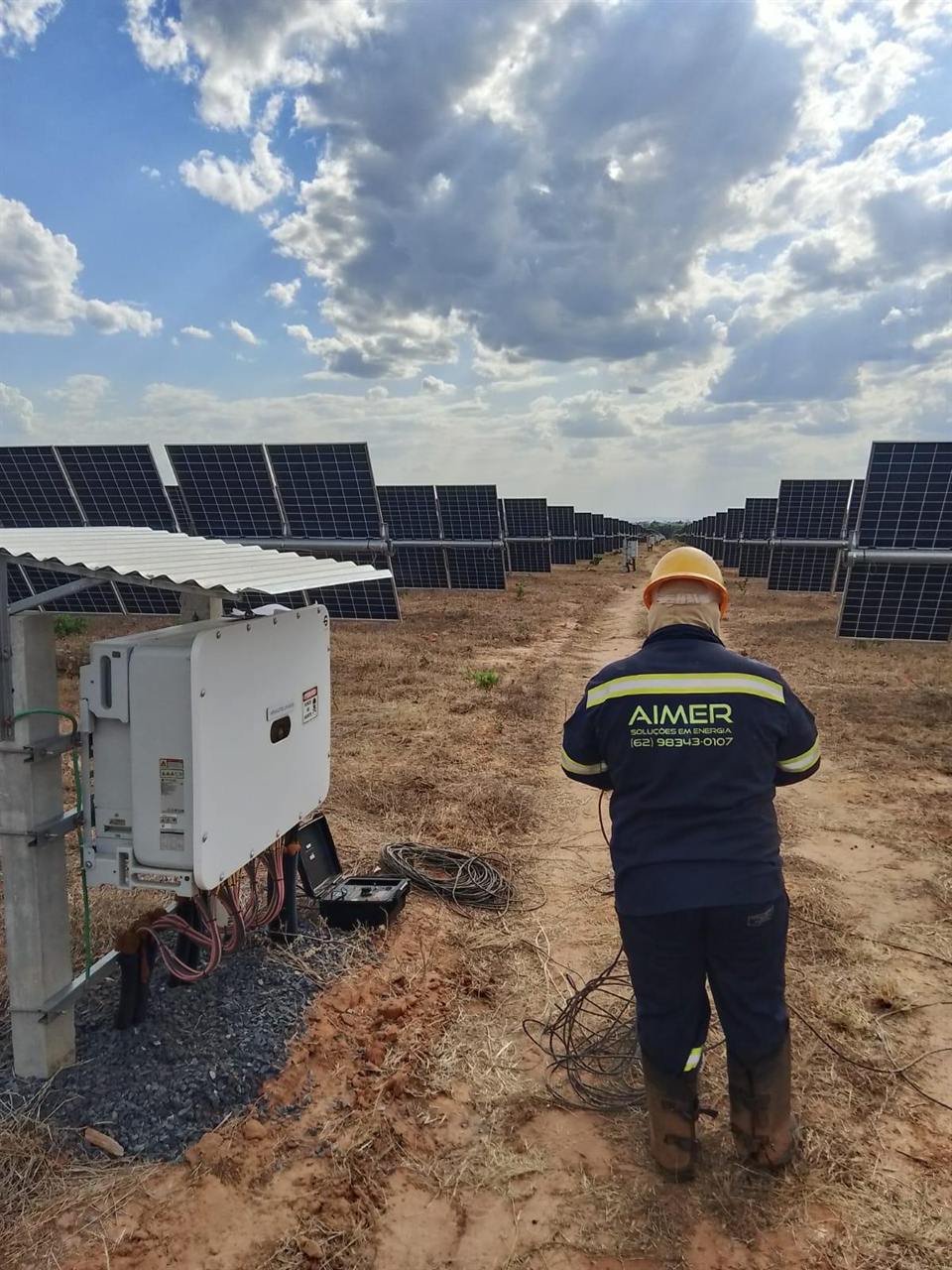 Técnico da Aimer medindo continuidade elétrica junto a um inversor na usina solar em Arinos (MG)