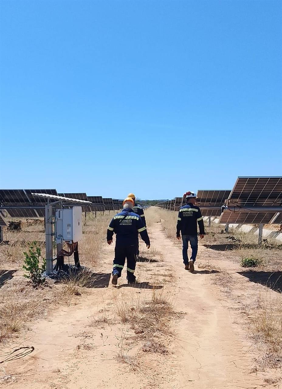 Dois técnicos da Aimer caminhando entre as fileiras de placas durante a inspeção